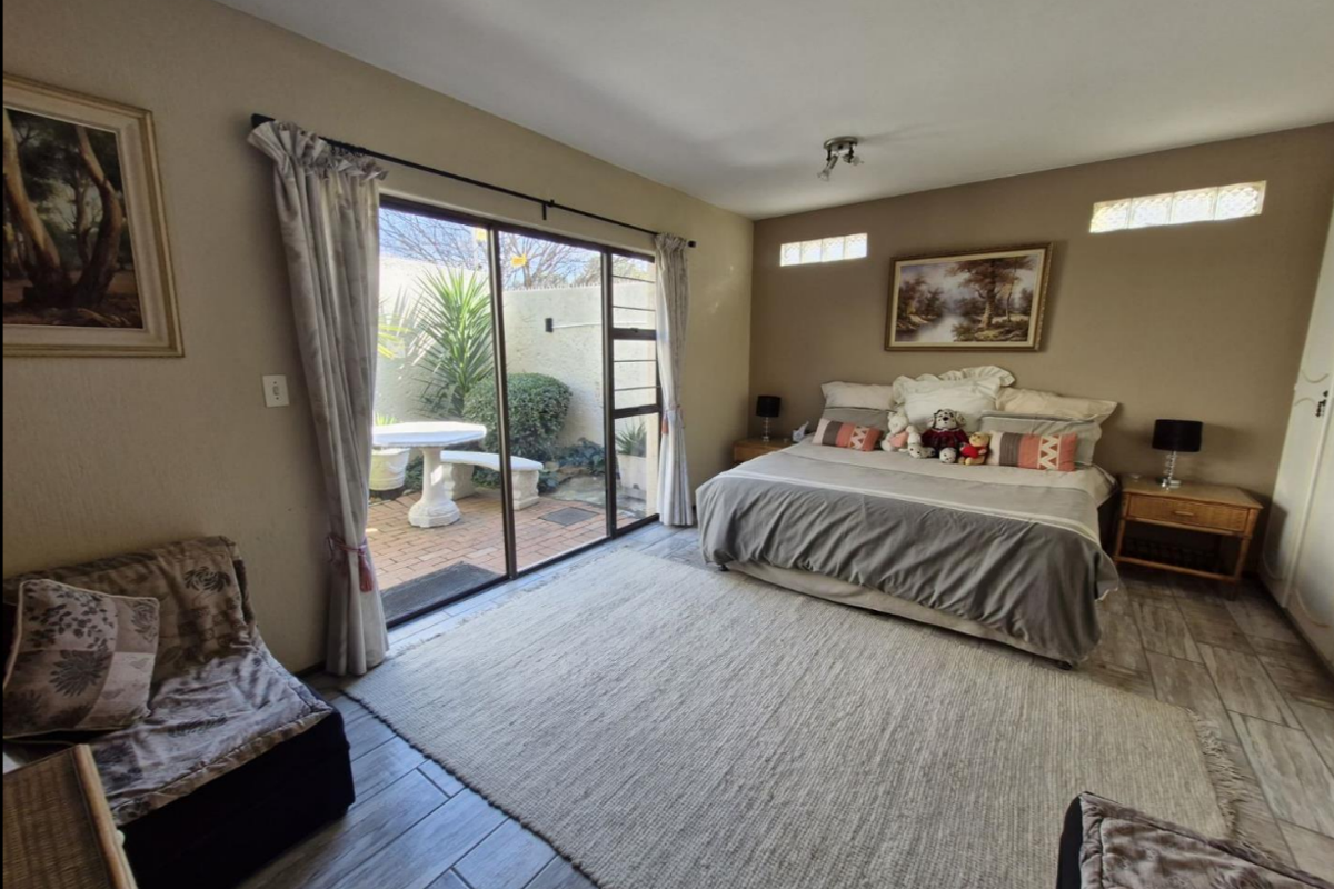 Spacious bedroom featuring tiled flooring, high-level clerestory windows, and sliding glass doors providing direct access to a private paved patio area.