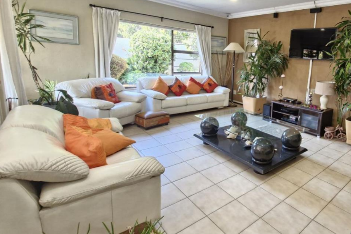 Spacious living room featuring large windows, neutral ceramic floor tiles, and a feature wall, offering a comfortable and bright living environment.