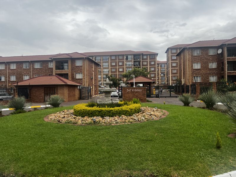 Exterior view of the Daffodil Gardens apartment complex, featuring brick facade buildings, landscaped garden areas, and a central fountain at the entrance.