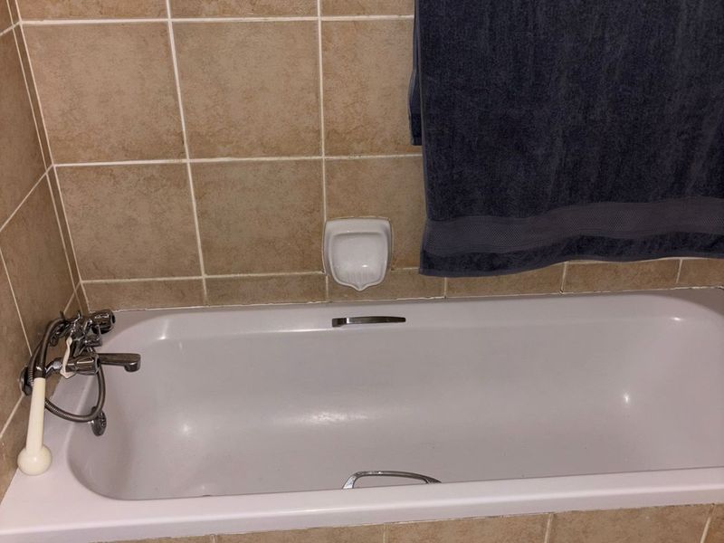 A standard bathroom featuring a built-in bathtub with tiled surround and chrome faucet fixtures.