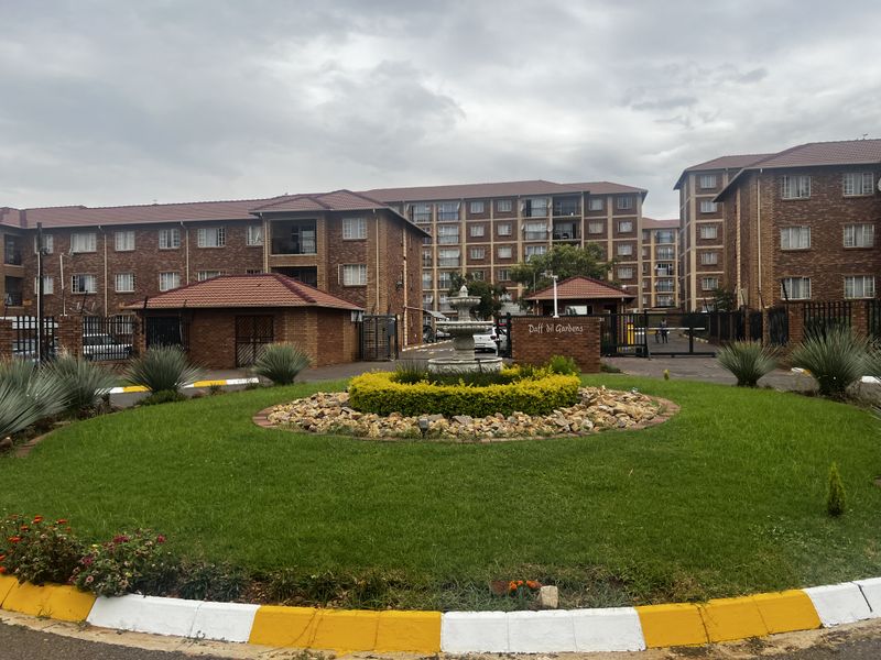 Exterior view of the Daffodil Gardens apartment complex, featuring brick facade buildings, a landscaped circular garden, and a central fountain at the entrance.