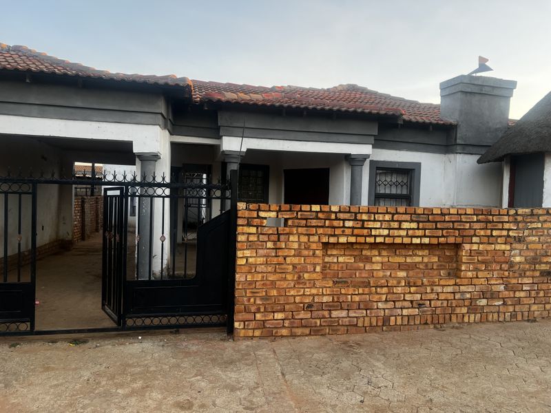 Front elevation of a single-story house featuring a brick boundary wall, covered entrance area, and tiled roof.
