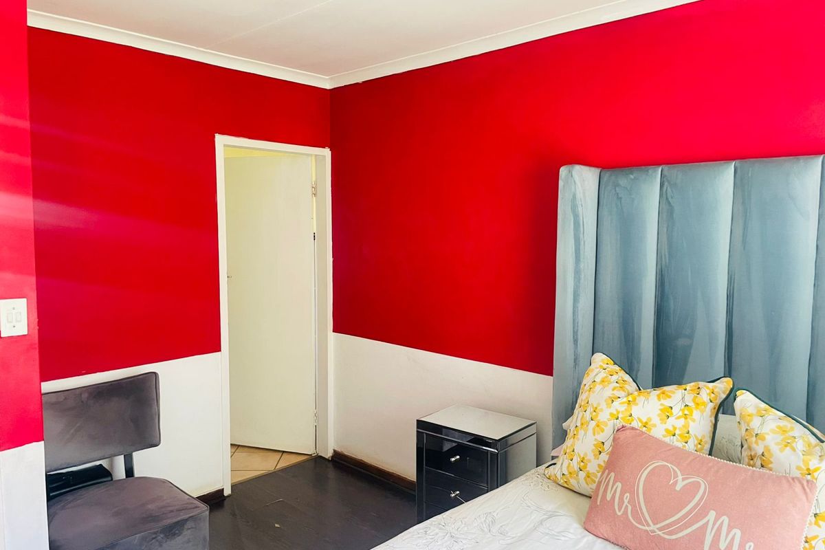 A bedroom featuring dark flooring and bold two-tone wall paint, providing a distinct aesthetic for the sleeping area.