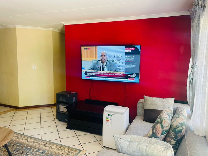 A living room featuring tiled flooring and a bold red accent wall, providing a functional space for relaxation and entertainment.