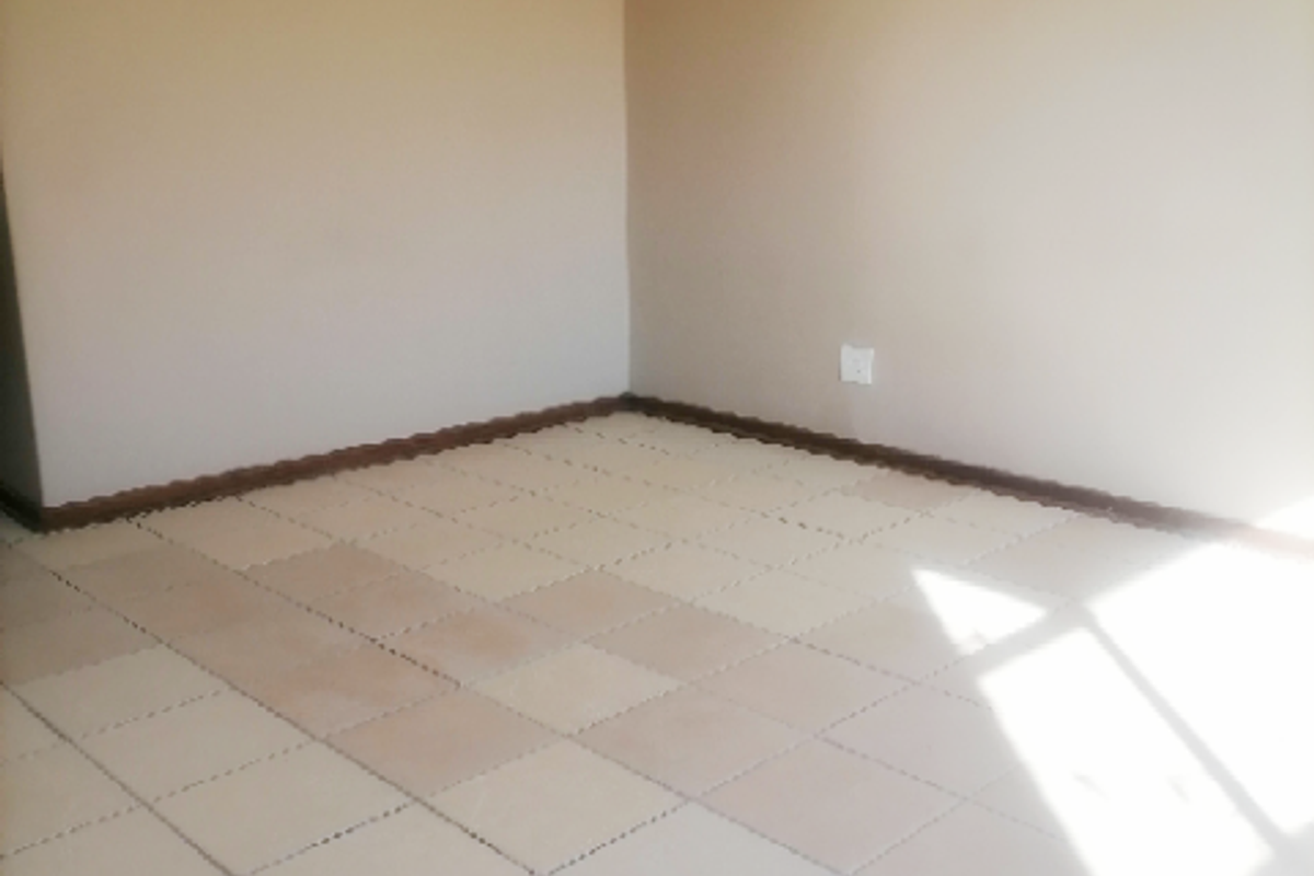 An empty bedroom featuring neutral painted walls and tiled flooring, providing a blank canvas for personalization.