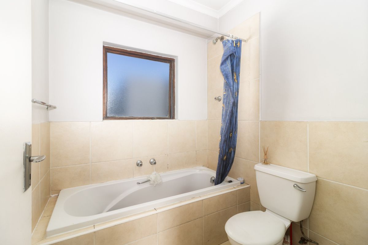 A functional bathroom featuring a built-in bathtub with shower attachment, tiled surround, and a standard toilet.