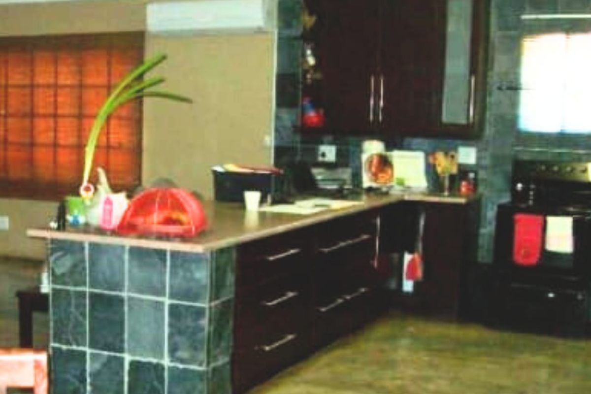A kitchen featuring dark wood cabinetry, stone-tiled breakfast bar, and integrated appliances, offering a functional layout with a neutral color palette.
