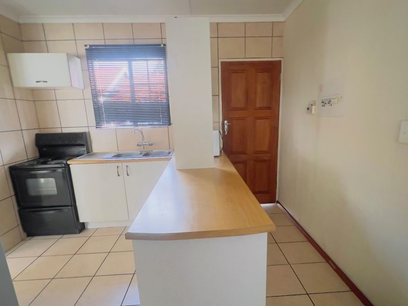 Functional kitchen featuring tiled flooring, built-in cabinetry, a double sink, and a breakfast bar, providing a practical layout for daily meal preparation.