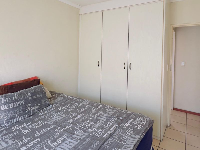 A bedroom featuring built-in wardrobes and tiled flooring, offering a functional space with neutral finishes.