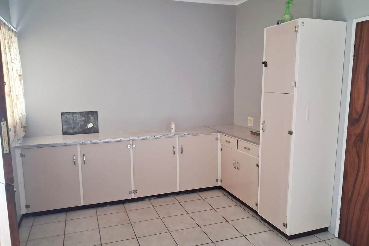 A functional kitchen space featuring tiled flooring, laminate countertops, and built-in cabinetry, offering a blank canvas for potential renovation and modernization.