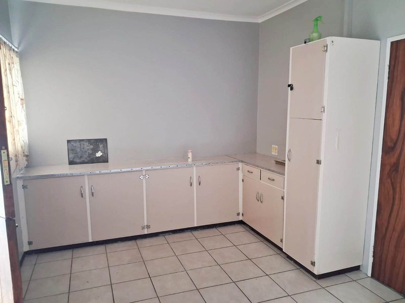 A functional kitchen space featuring tiled flooring, laminate countertops, and built-in cabinetry, offering a blank canvas for potential renovation and modernization.