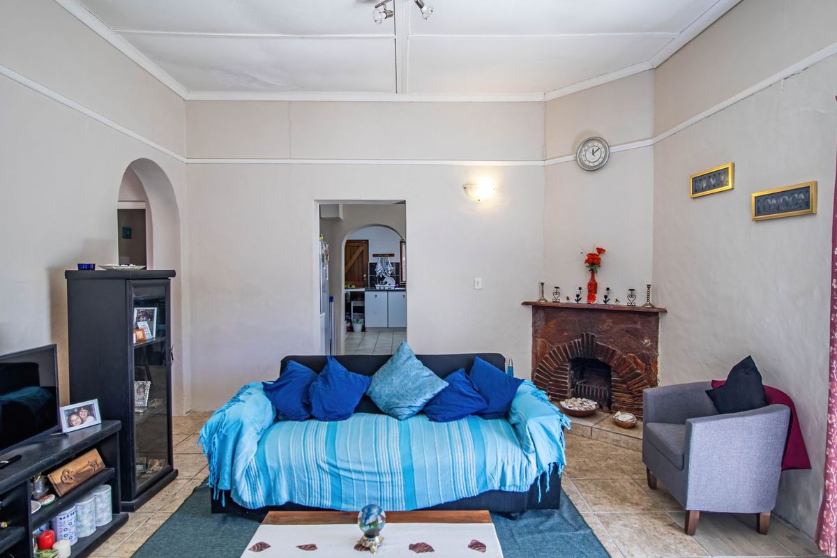 A living room featuring a traditional brick fireplace, tiled flooring, and arched doorways leading to adjacent living spaces.