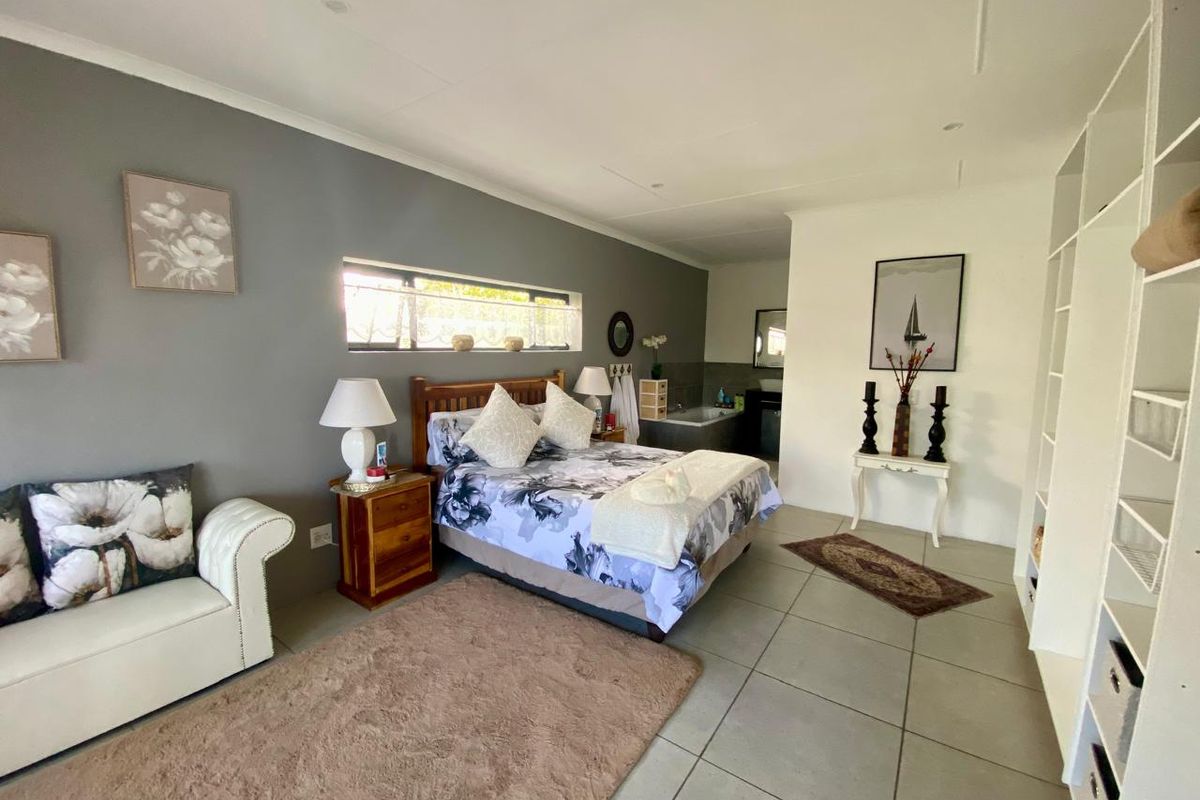 Spacious bedroom featuring tiled flooring, built-in shelving, and an integrated en-suite bathroom area with a bathtub.