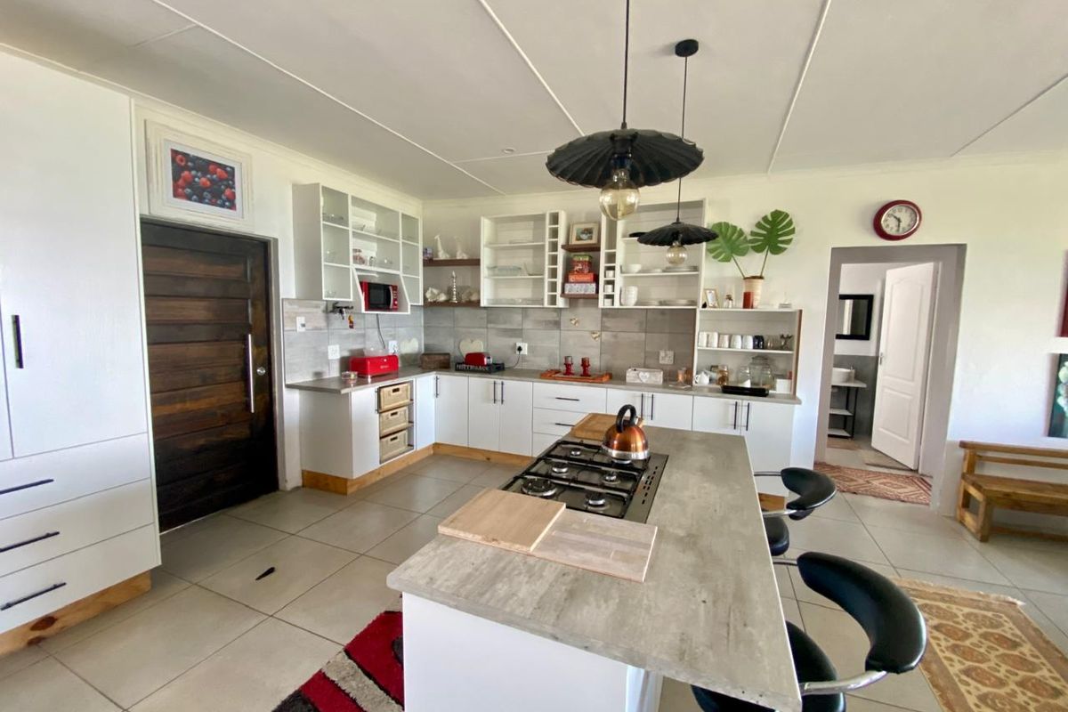 Modern open-plan kitchen featuring a central island with a built-in gas hob, ample cabinetry, and tiled flooring throughout.