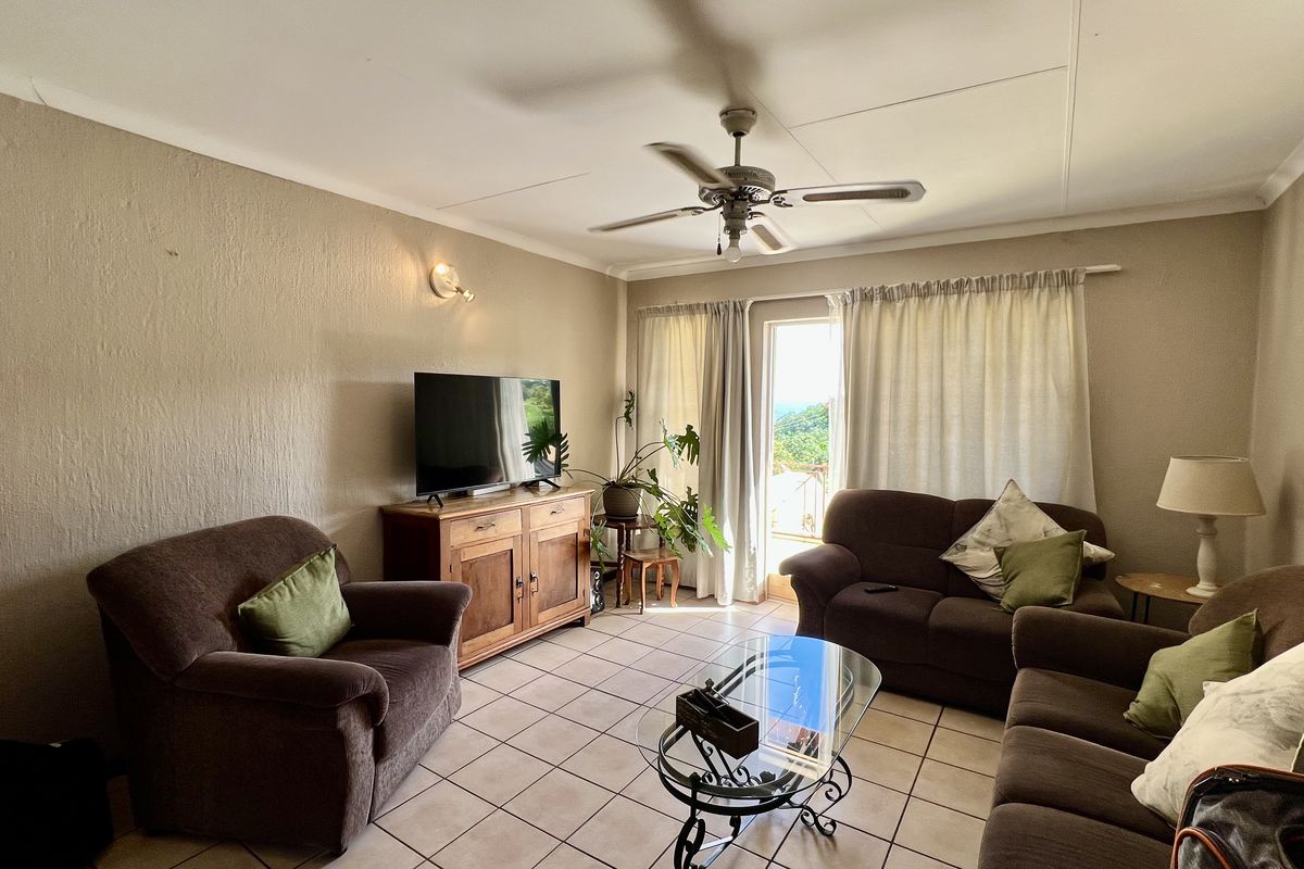 A comfortable living room featuring tiled flooring, a ceiling fan, and direct access to an outdoor area through a sliding glass door.