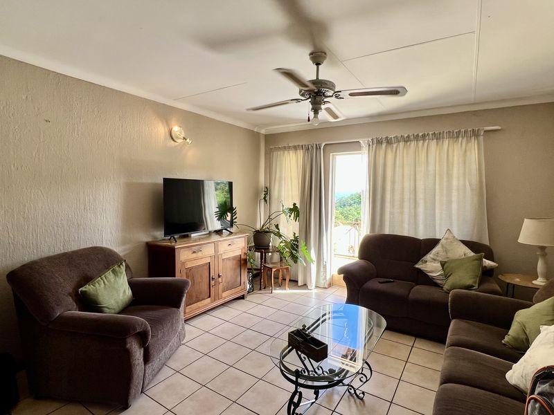 A comfortable living room featuring tiled flooring, a ceiling fan, and direct access to an outdoor area through a sliding glass door.