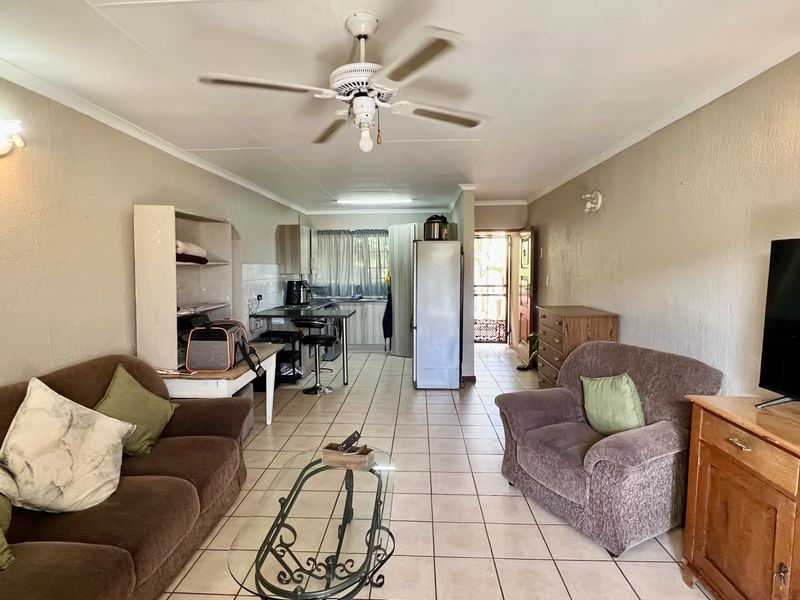 Open-plan living area featuring tiled flooring, a ceiling fan, and an integrated kitchen space with built-in cabinetry.