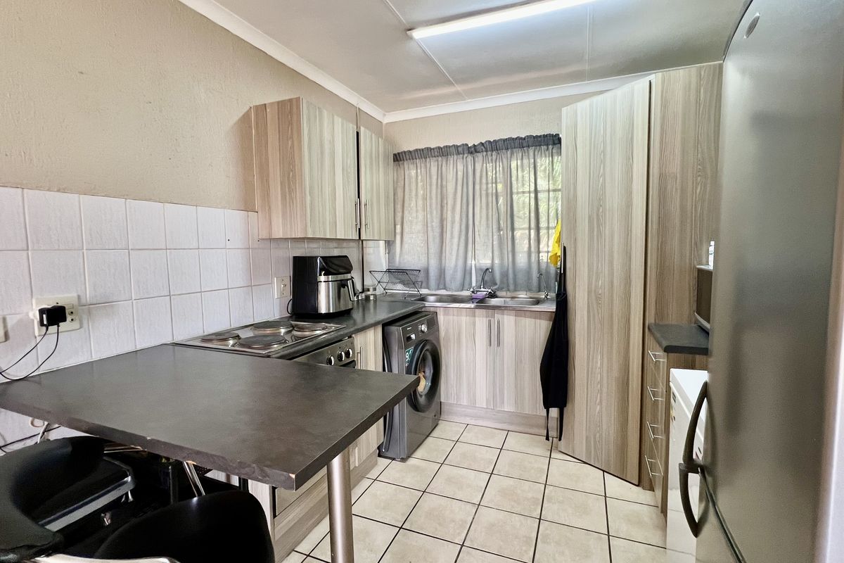 Functional kitchen featuring laminate cabinetry, built-in electric hob and oven, double sink, and a convenient breakfast bar area.