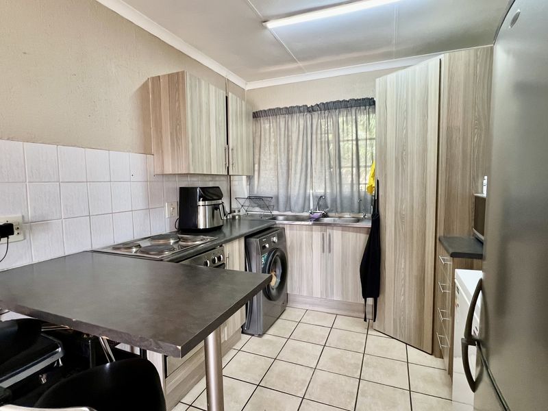 Functional kitchen featuring laminate cabinetry, built-in electric hob and oven, double sink, and a convenient breakfast bar area.