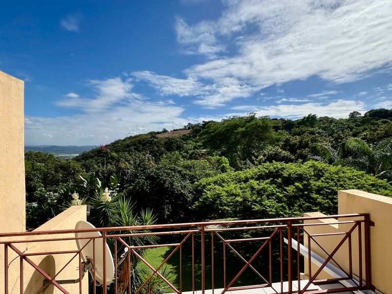 A balcony featuring a metal balustrade with expansive views of the surrounding lush green landscape and hills.