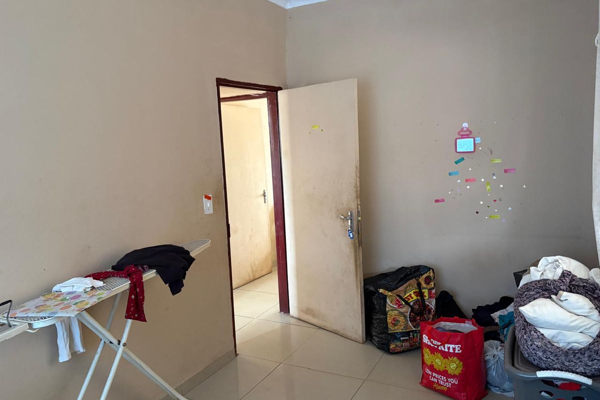 A simple bedroom featuring tiled flooring and a standard interior door leading to an adjacent hallway.