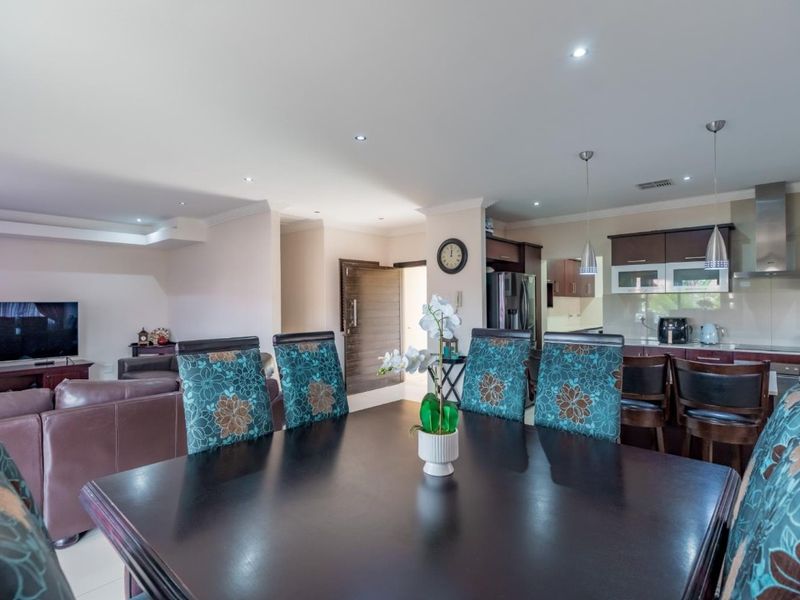 Spacious open-plan living and dining area featuring a modern kitchen with dark cabinetry, stainless steel extractor fan, and recessed lighting throughout.