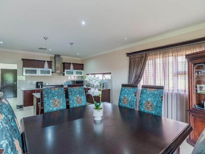 Open-plan dining and kitchen area featuring dark wood cabinetry, modern lighting, and tiled flooring, creating a functional and cohesive living space.