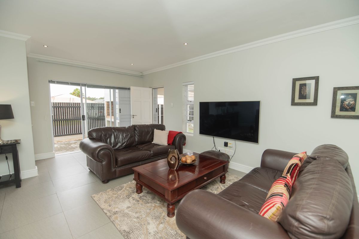 A bright and spacious living room featuring tiled flooring, recessed lighting, and sliding glass doors that open to an outdoor patio area.