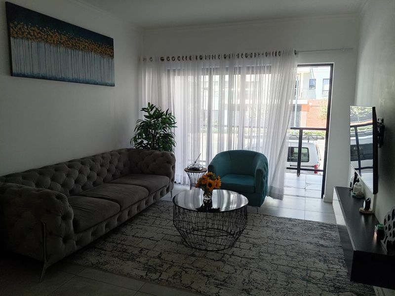 A well-lit living room featuring tiled flooring and a sliding glass door that opens onto a private balcony.