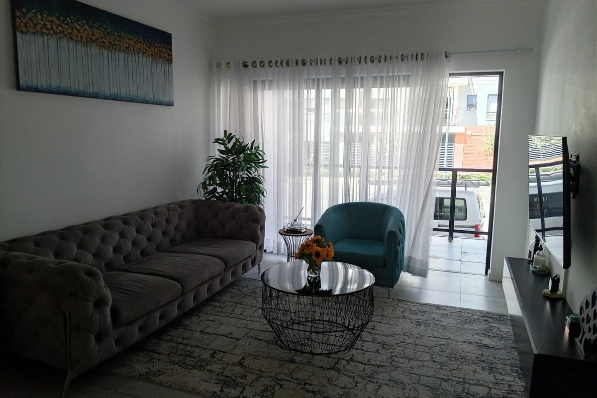 A well-lit living room featuring tiled flooring and a sliding glass door that opens onto a private balcony.