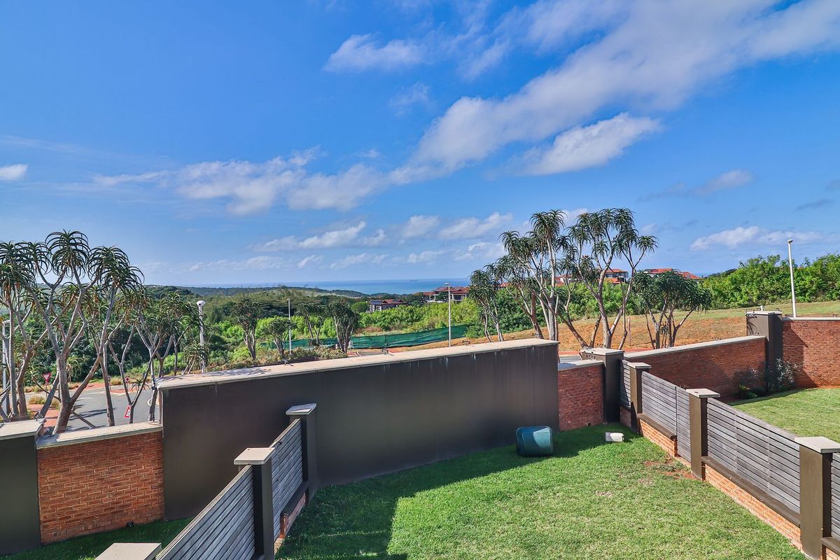 Elevated view of the property's rear garden area, featuring brick boundary walls, timber fencing, and expansive coastal landscape views.