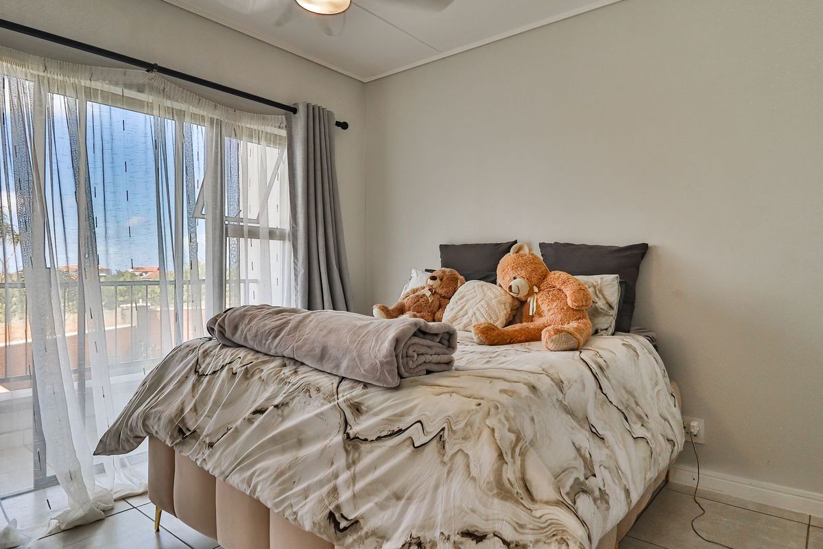 A bright bedroom featuring large sliding glass doors that open onto a private balcony, providing natural light and outdoor access.