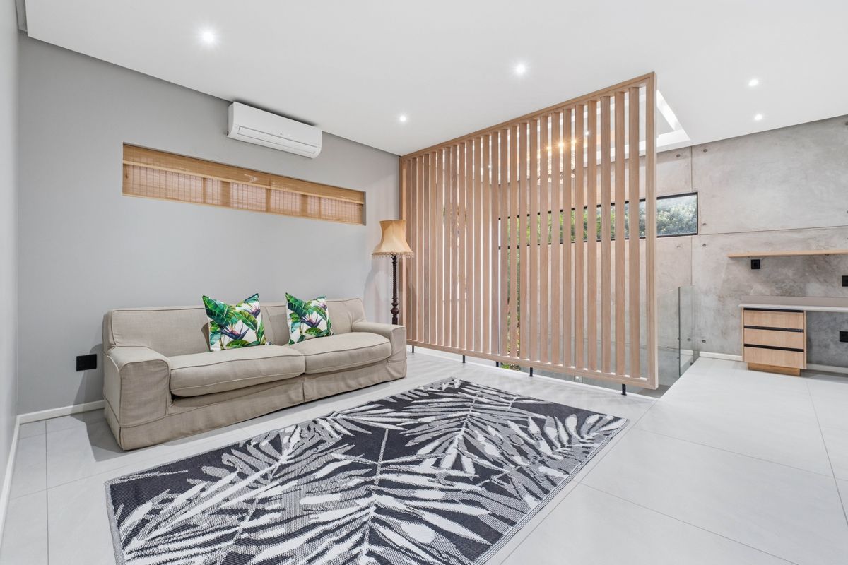 Modern living area featuring a timber slat room divider, polished tile flooring, recessed lighting, and a wall-mounted air conditioning unit.