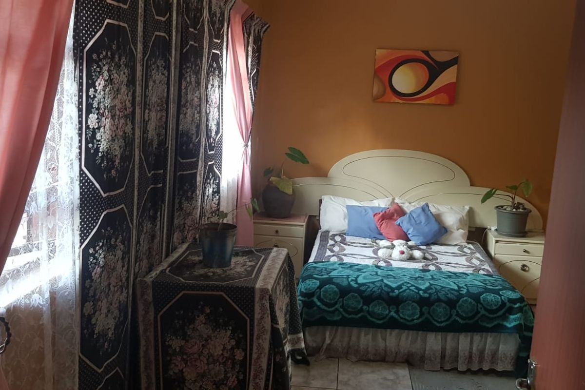 A bedroom featuring tiled flooring and a built-in headboard, providing a functional sleeping space.