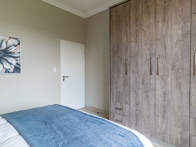 A well-maintained bedroom featuring neutral wall tones, crown molding, and extensive built-in wooden cabinetry with integrated storage drawers.