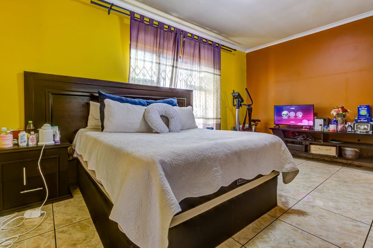 A bedroom featuring tiled flooring and dual-tone painted walls, providing a functional space with natural light from the window.