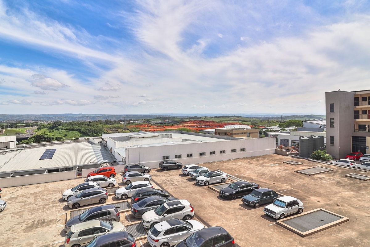 An elevated aerial view of an apartment complex parking area with surrounding landscape and distant horizon views.