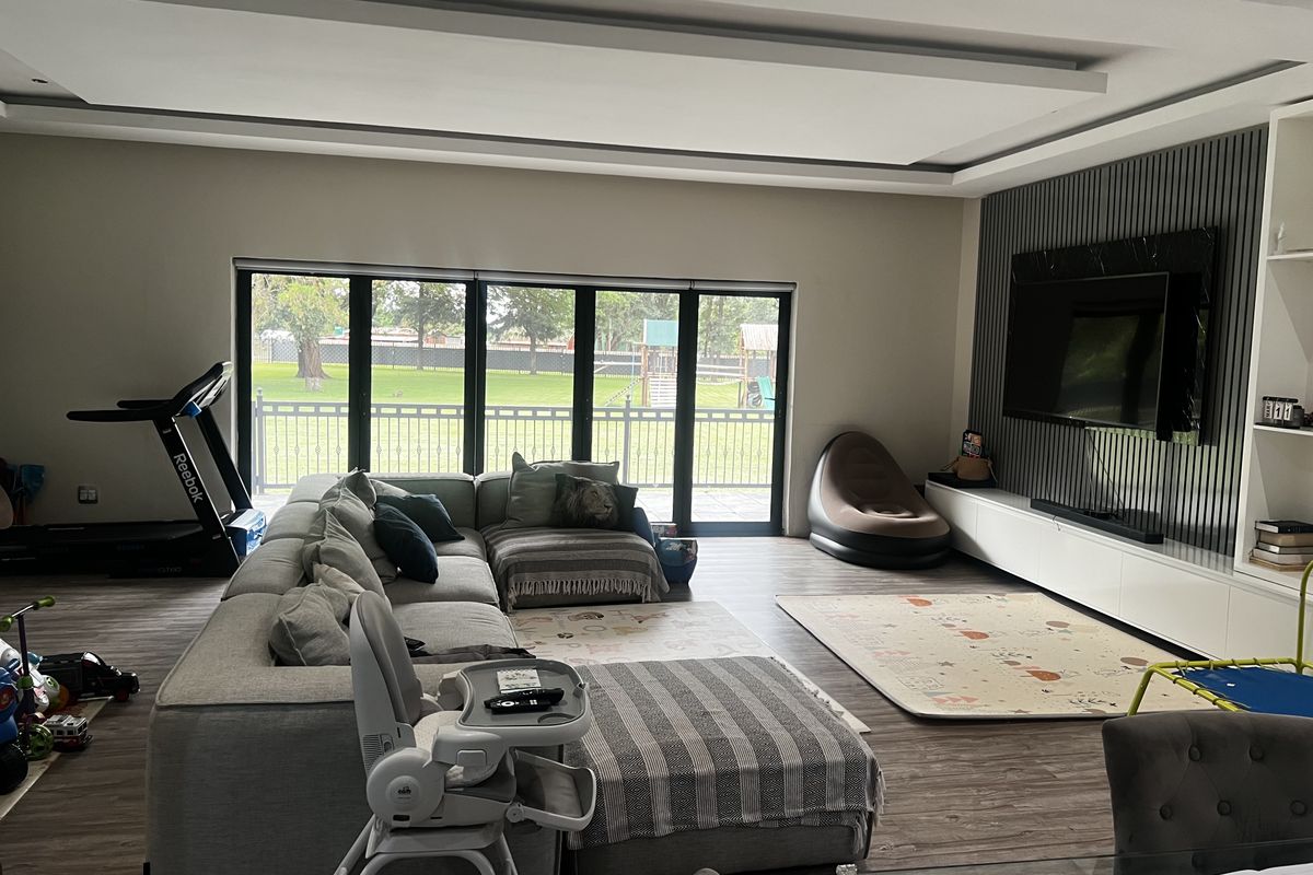 Spacious living room featuring modern recessed ceiling lighting, wood-look flooring, and large sliding glass doors providing direct access to the rear garden.