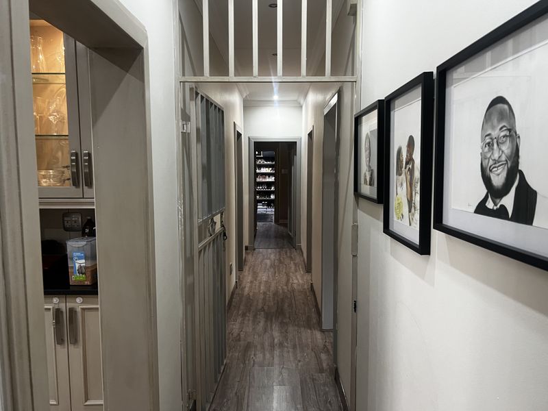 A well-maintained hallway featuring wood-look flooring, recessed lighting, and a secure metal gate, providing access to multiple rooms within the home.
