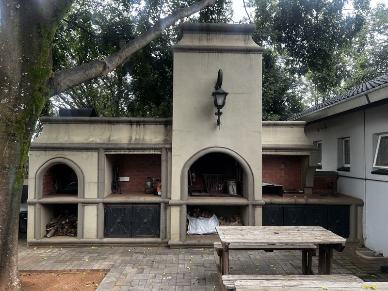 Outdoor entertainment area featuring a large built-in masonry braai or barbecue station with integrated storage compartments and a decorative wall-mounted light fixture.