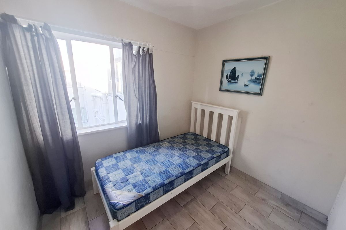 A compact bedroom featuring tiled flooring and a window, providing a functional space for a single bed.