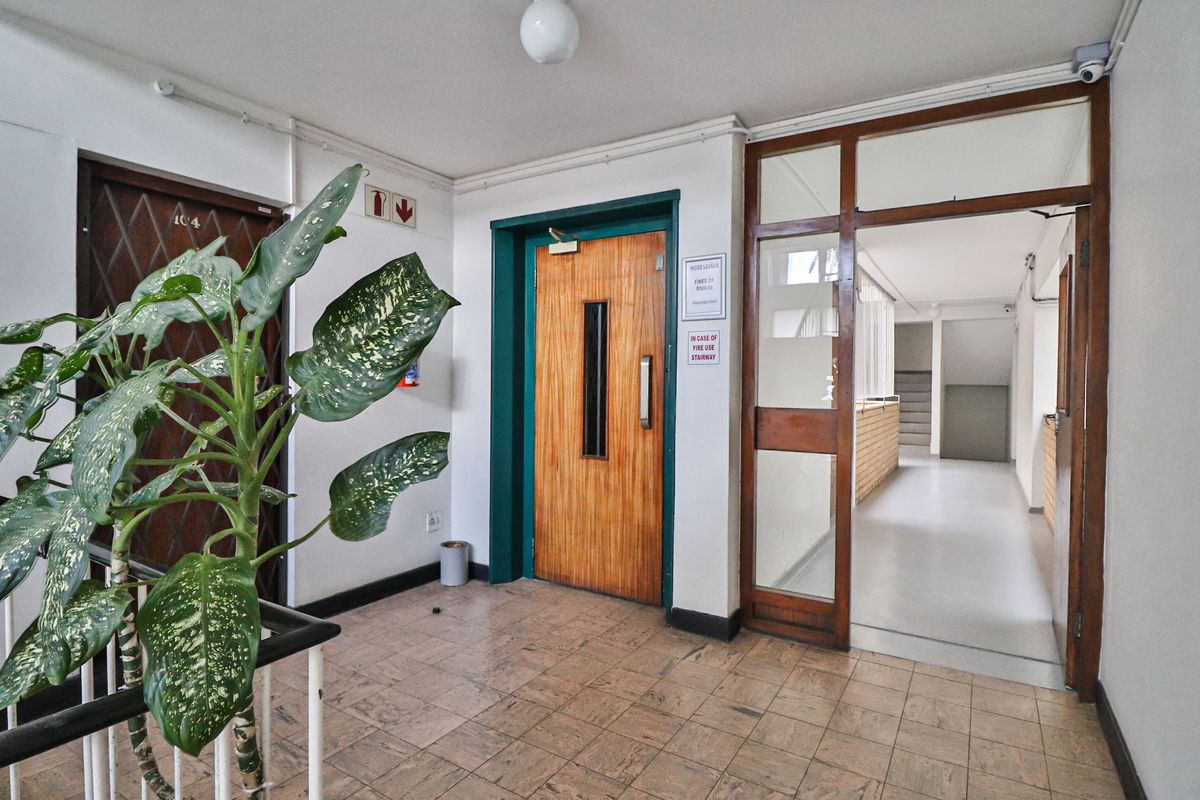 Communal apartment building entrance lobby featuring elevator access, tiled flooring, and a secure doorway leading to the stairwell.