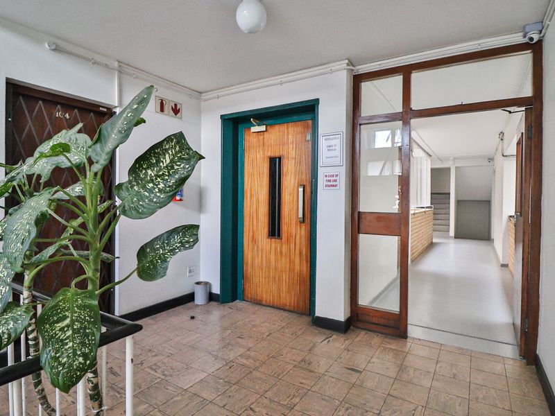 Communal apartment building entrance lobby featuring elevator access, tiled flooring, and a secure doorway leading to the stairwell.