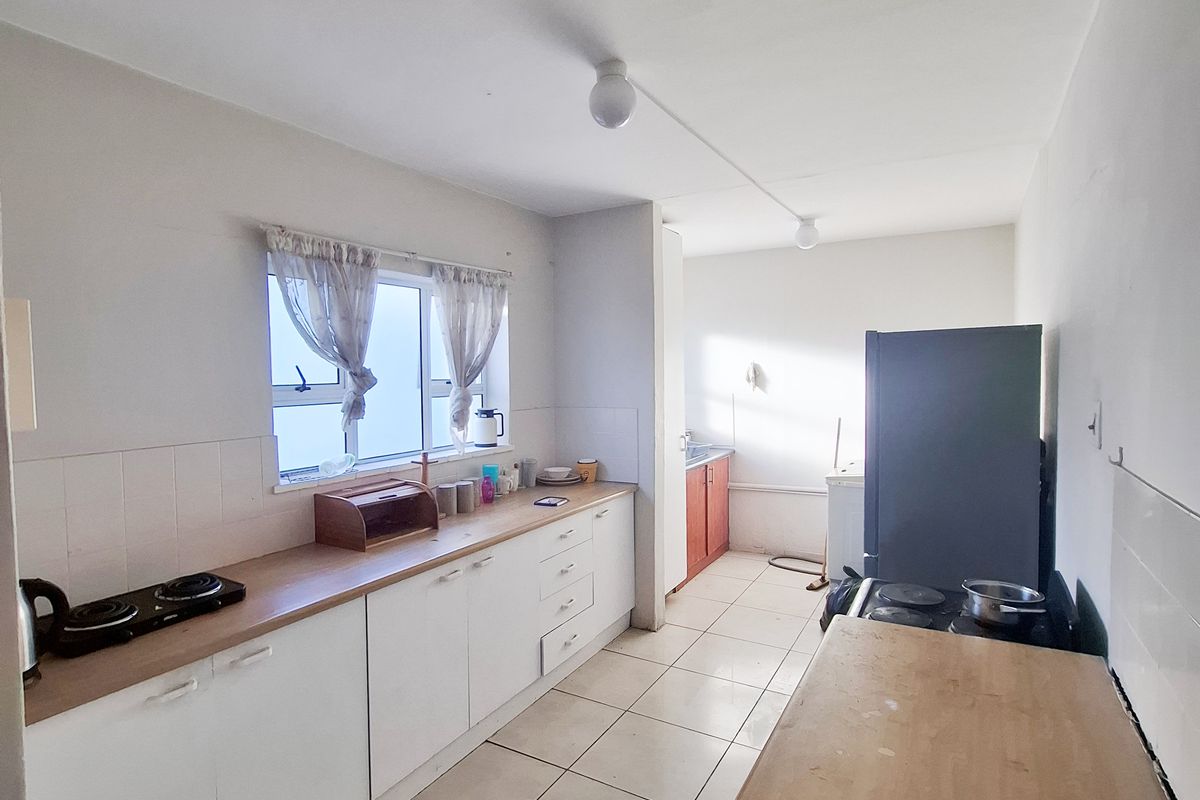 A functional kitchen featuring built-in cabinetry, tiled flooring, and a hob, offering a practical layout with natural light from the window.