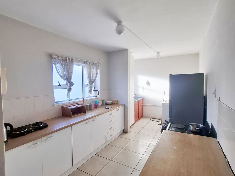 A functional kitchen featuring built-in cabinetry, tiled flooring, and a hob, offering a practical layout with natural light from the window.