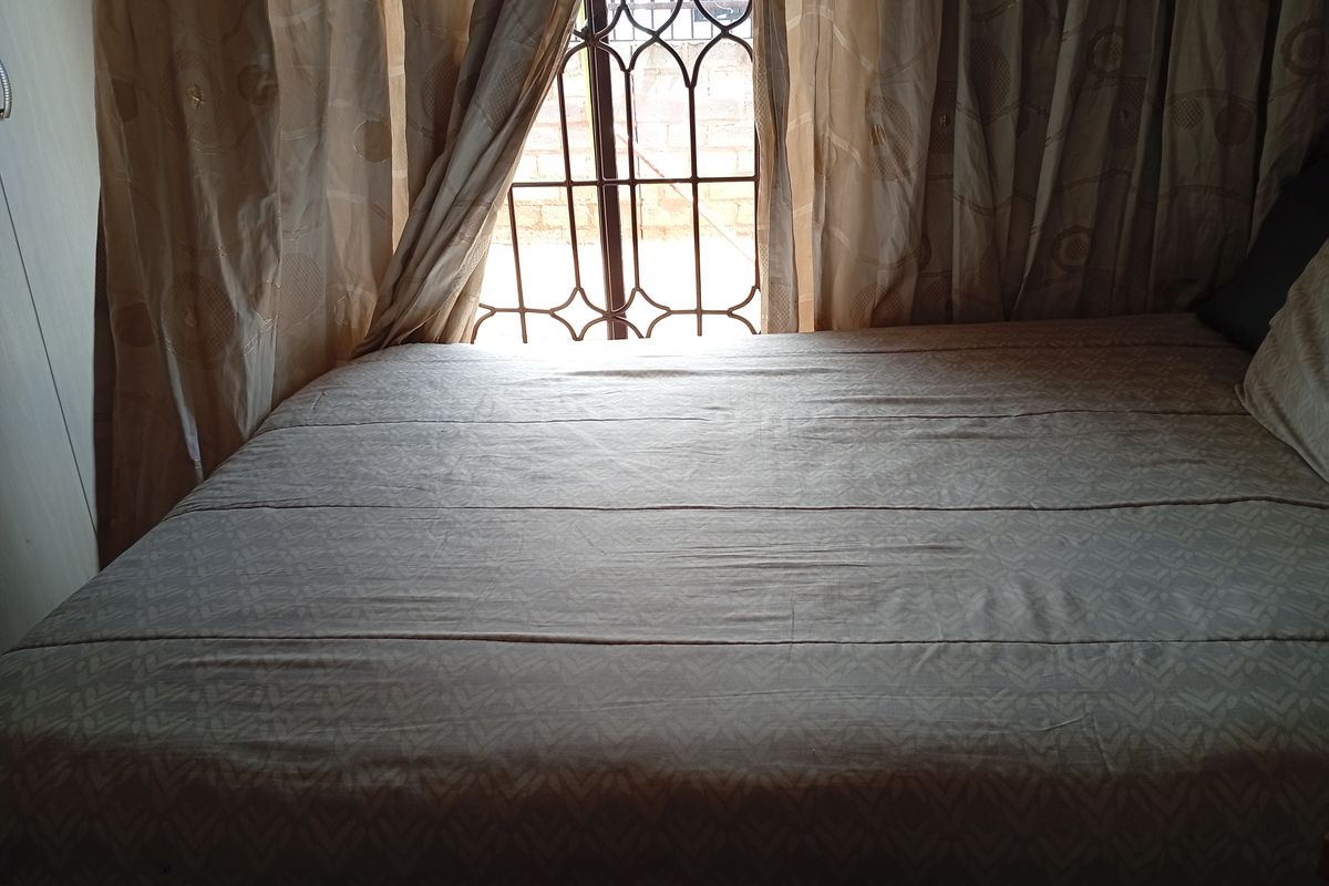 A bedroom featuring a window with decorative metal security bars and integrated curtain tracks.