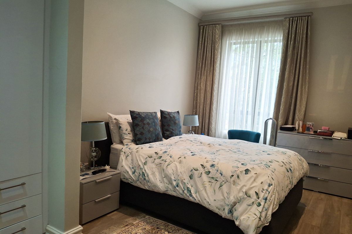 A well-maintained bedroom featuring built-in cabinetry, recessed ceiling lighting, and large windows with floor-to-ceiling curtains.