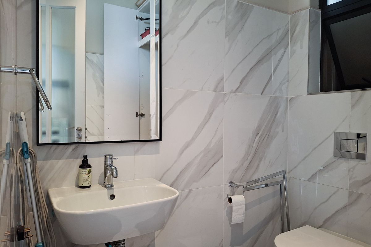 Modern bathroom featuring marble-look wall tiles, a wall-mounted basin with chrome faucet, and a concealed cistern toilet.