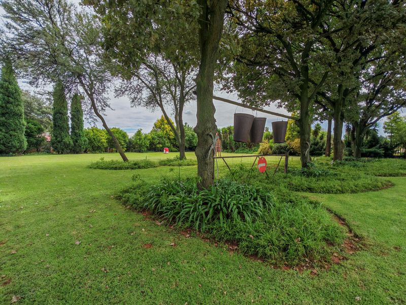 A spacious, well-established garden featuring mature trees, expansive lawn areas, and perimeter hedging, providing a private and tranquil outdoor setting.