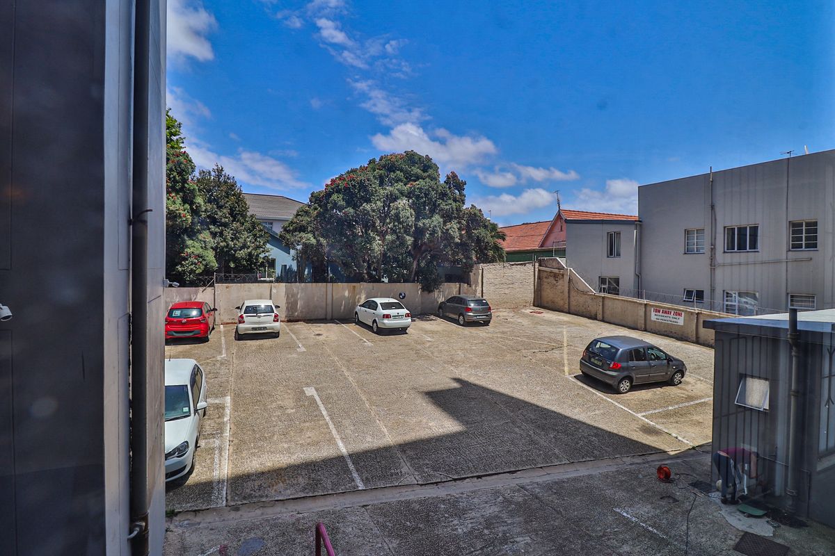 An elevated view of the apartment complex parking area, featuring marked bays and perimeter boundary walls.